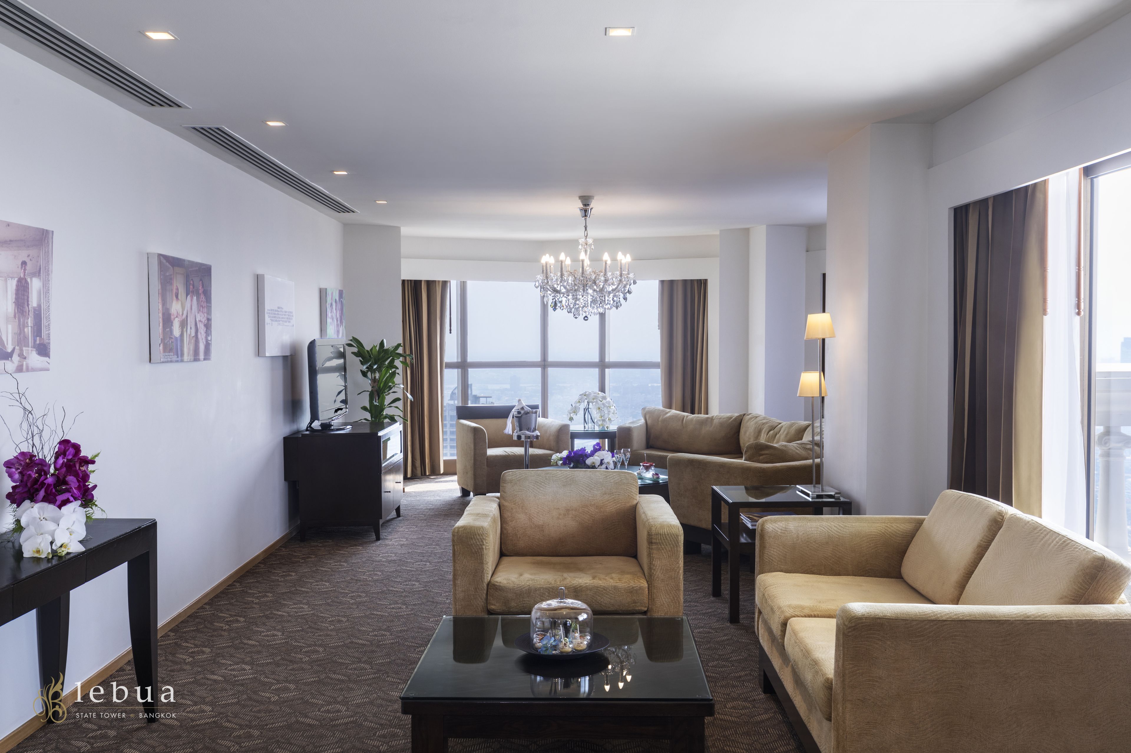 A hotel living room with a chandelier, two sofas, a coffee table, and artwork on the walls.
