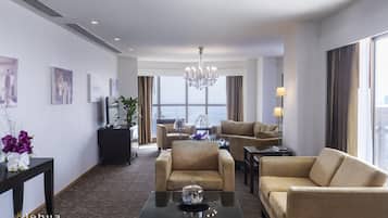 A hotel living room with a chandelier, two sofas, a coffee table, and artwork on the walls.