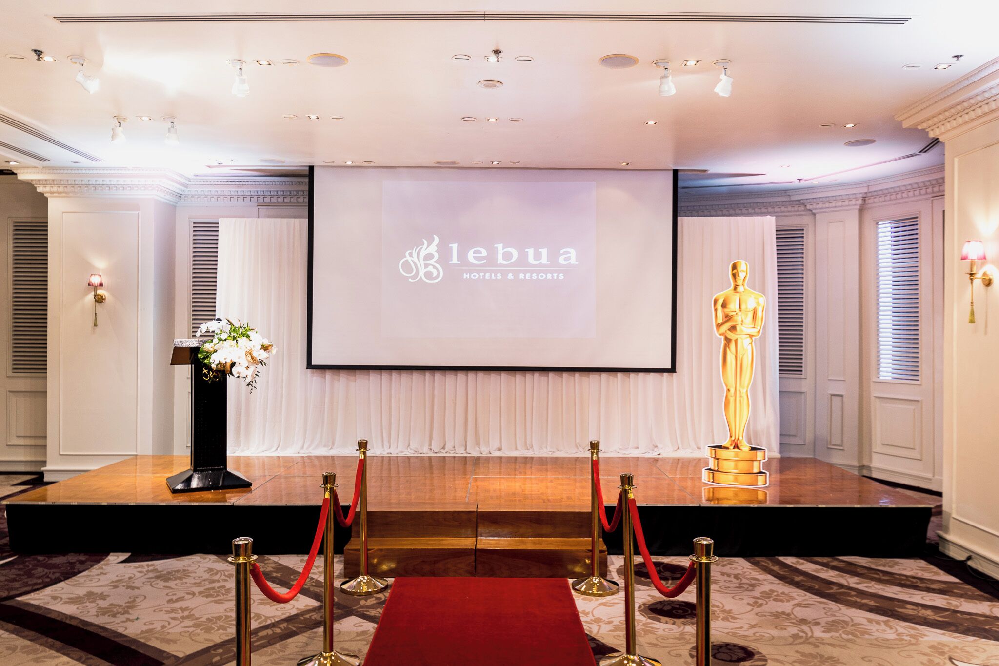 A stage with a podium, a red carpet, and a screen displaying 'lebu'a Hotels & Resorts' logo.