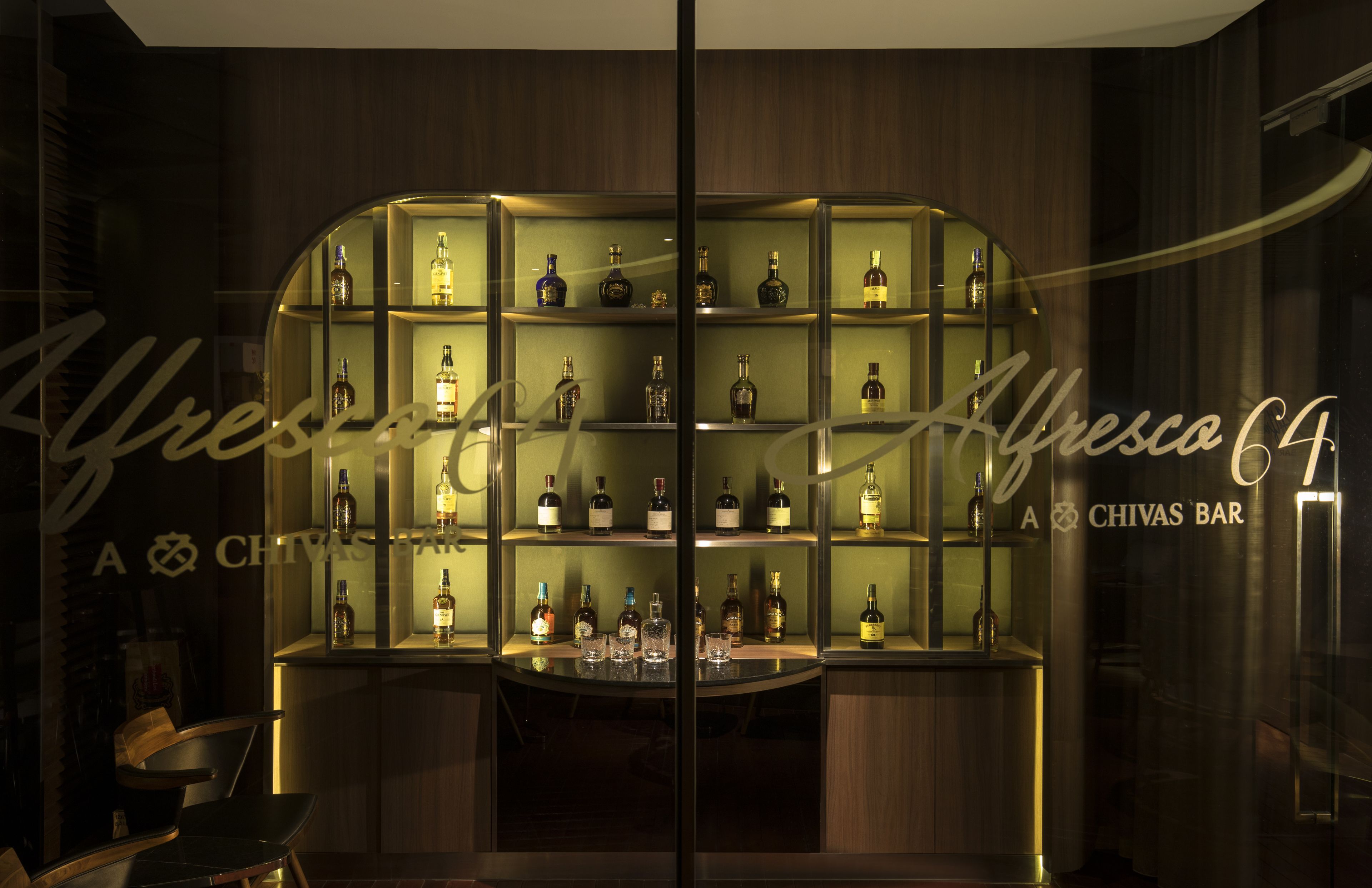 Eine Bar mit Regalen voller Spirituosenflaschen und Gläsern, einer Theke und einer Spiegelwand.