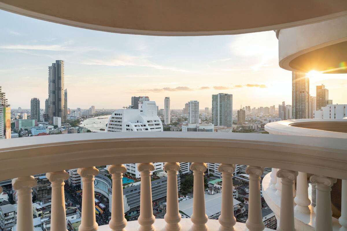 A balcony with a city view, featuring modern buildings and a clear sky.