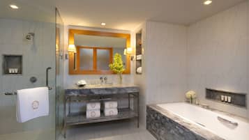 A modern bathroom with a glass shower enclosure, a marble vanity, a large mirror, and a freestanding bathtub.