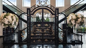 Una imponente entrada con una reja de hierro negro, flores blancas y el nombre "MEILA LUNA" sobre las escaleras.
