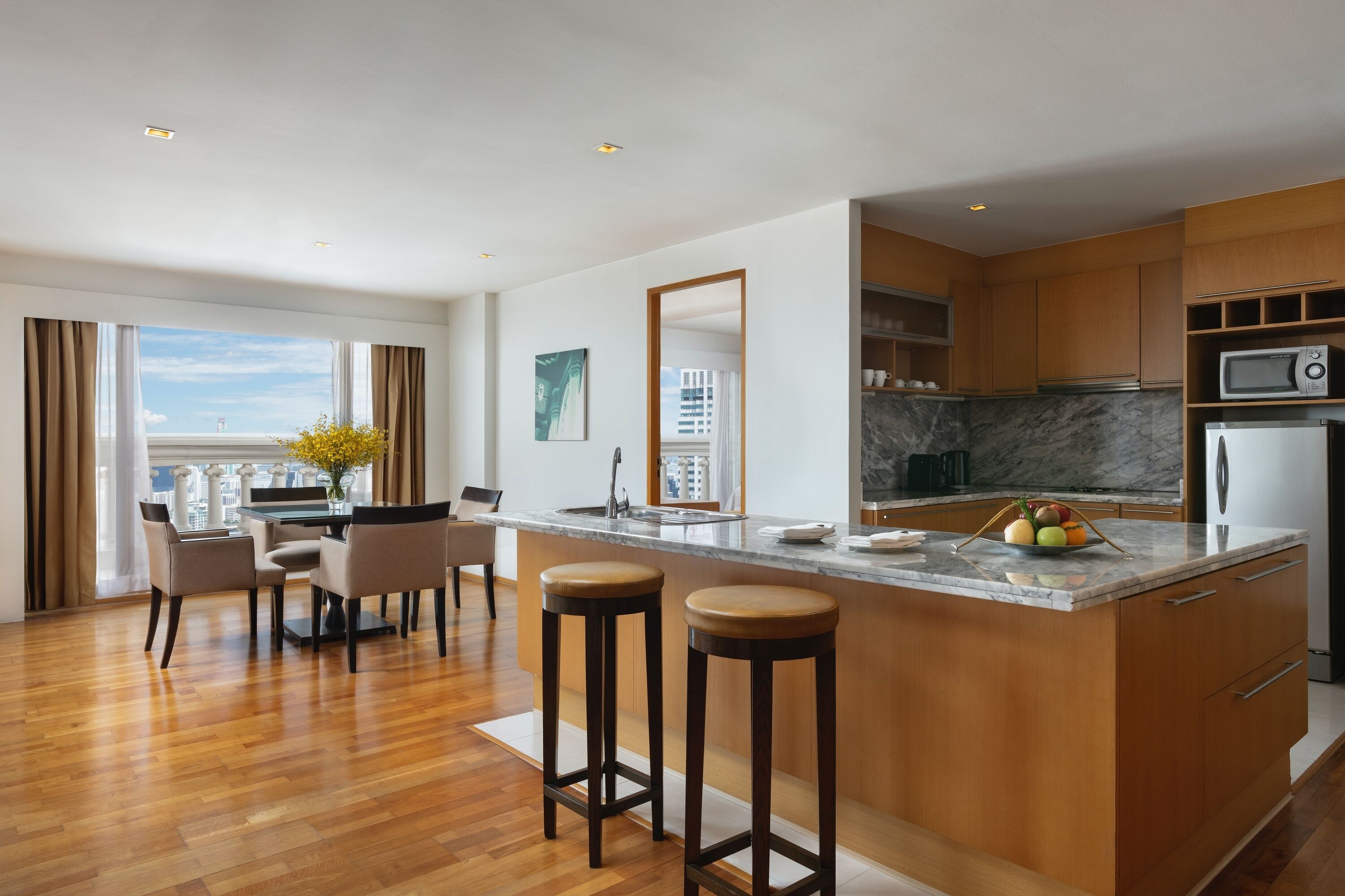 A modern kitchen with a marble countertop, wooden cabinets, and a built-in microwave.