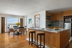 A modern kitchen with a marble countertop, wooden cabinets, and a built-in microwave.