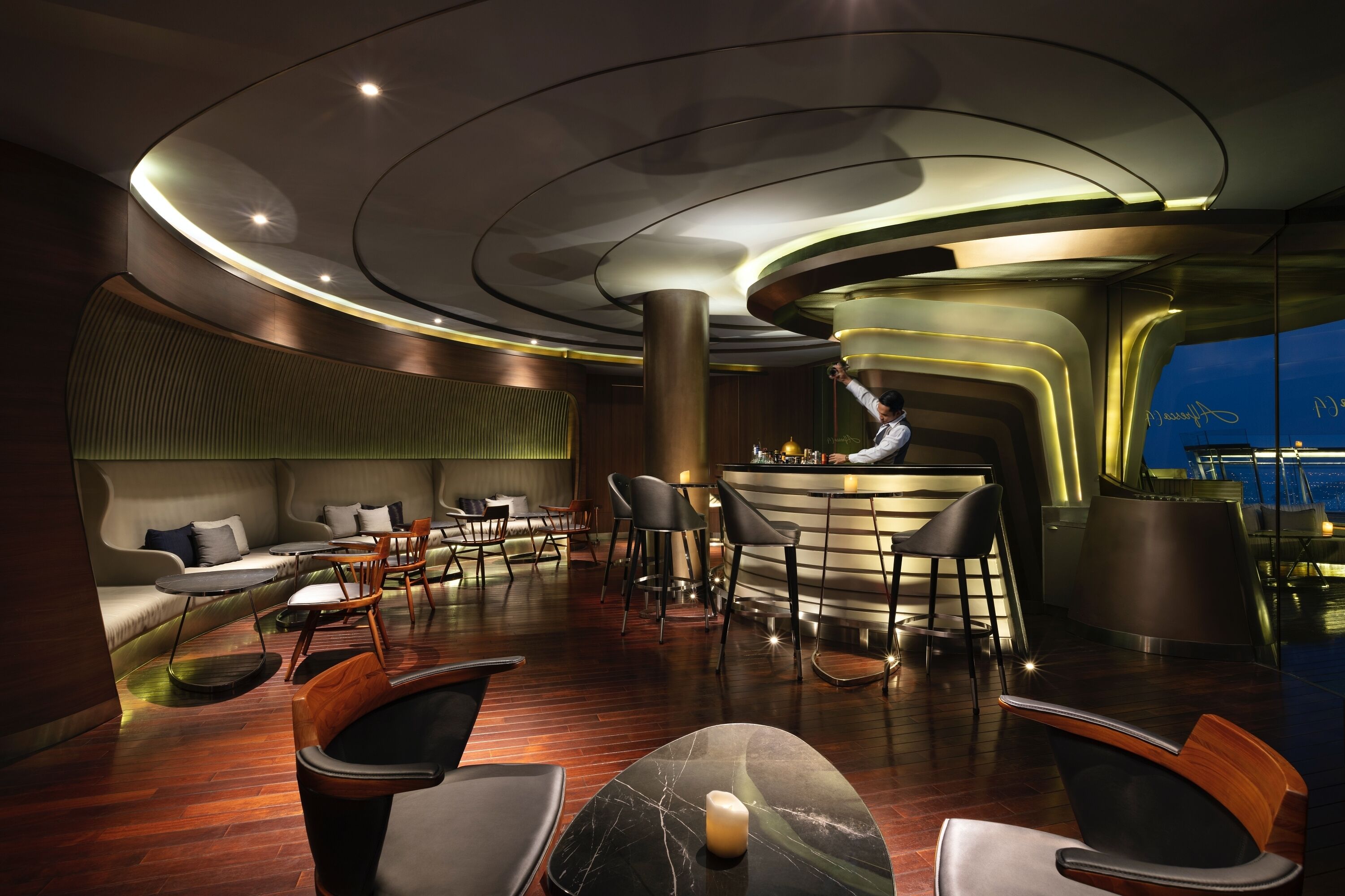 A modern bar area with a curved ceiling, wooden flooring, and bar stools.