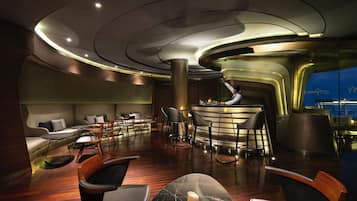 A modern bar area with a curved ceiling, wooden flooring, and bar stools.