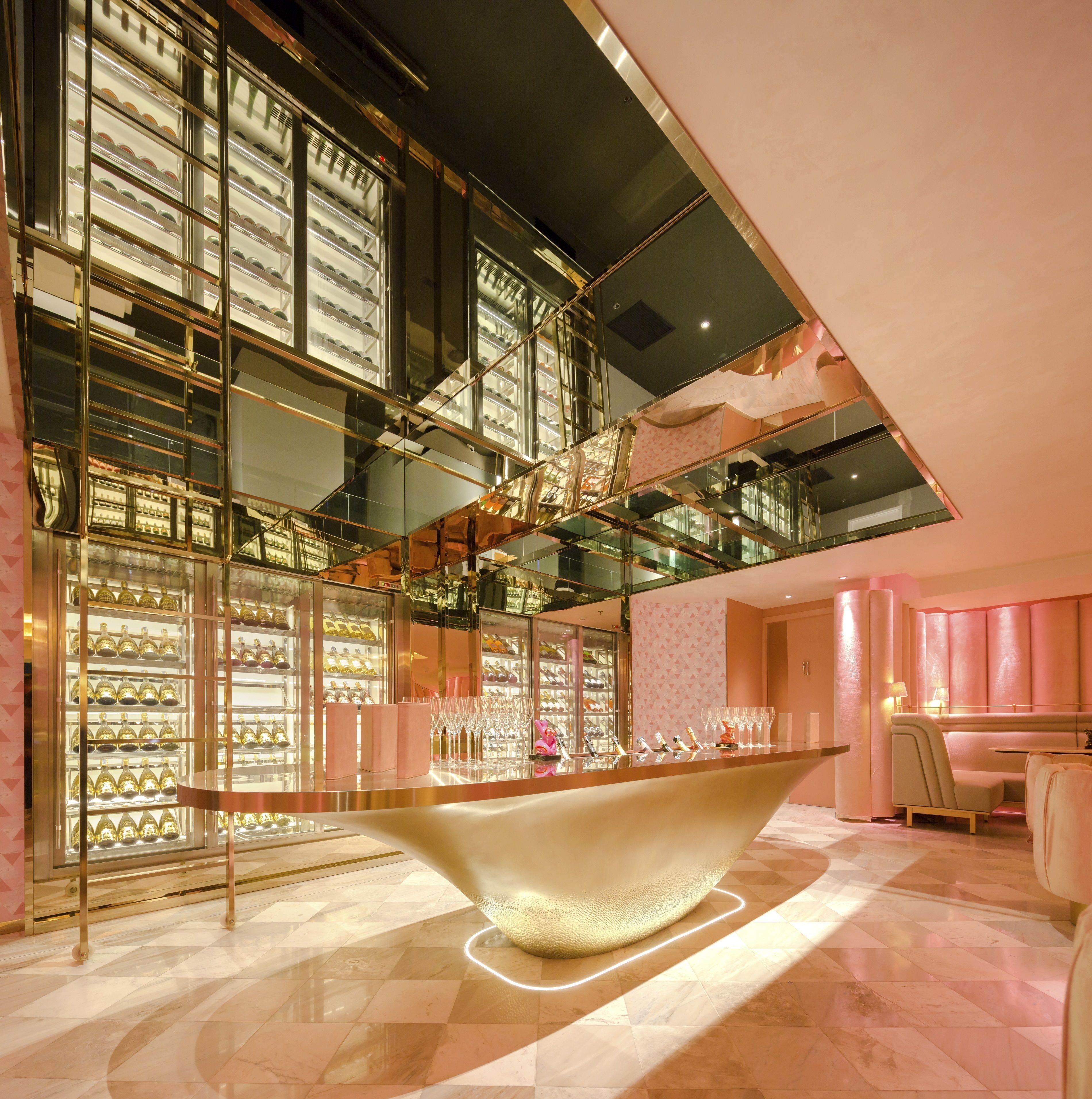 A modern interior with a central glass table, reflective surfaces, and a patterned wall.