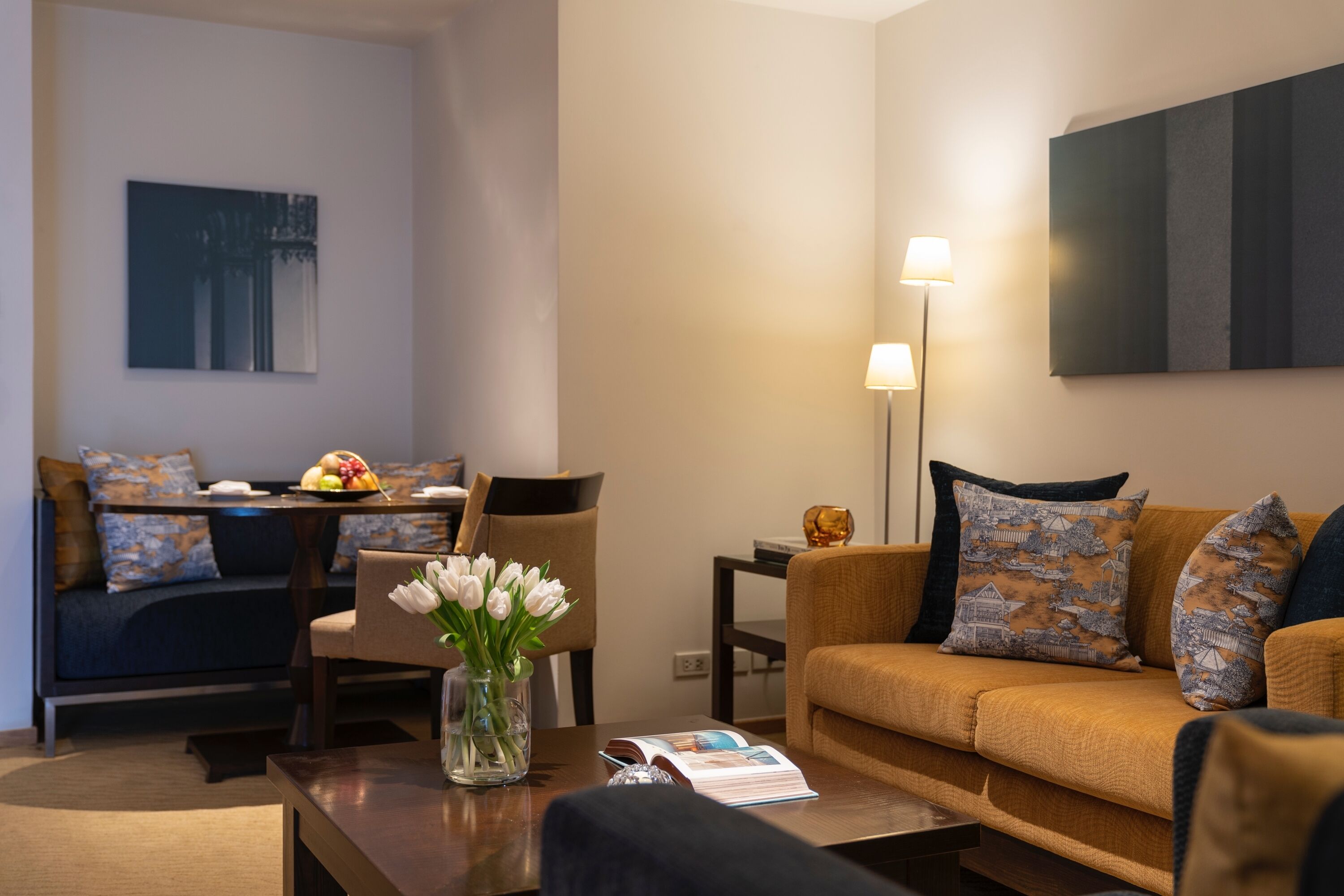 A modern living room with a sofa, coffee table, and a dining area with a table set for two.