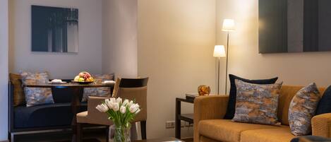 A modern living room with a sofa, coffee table, and a dining area with a table set for two.