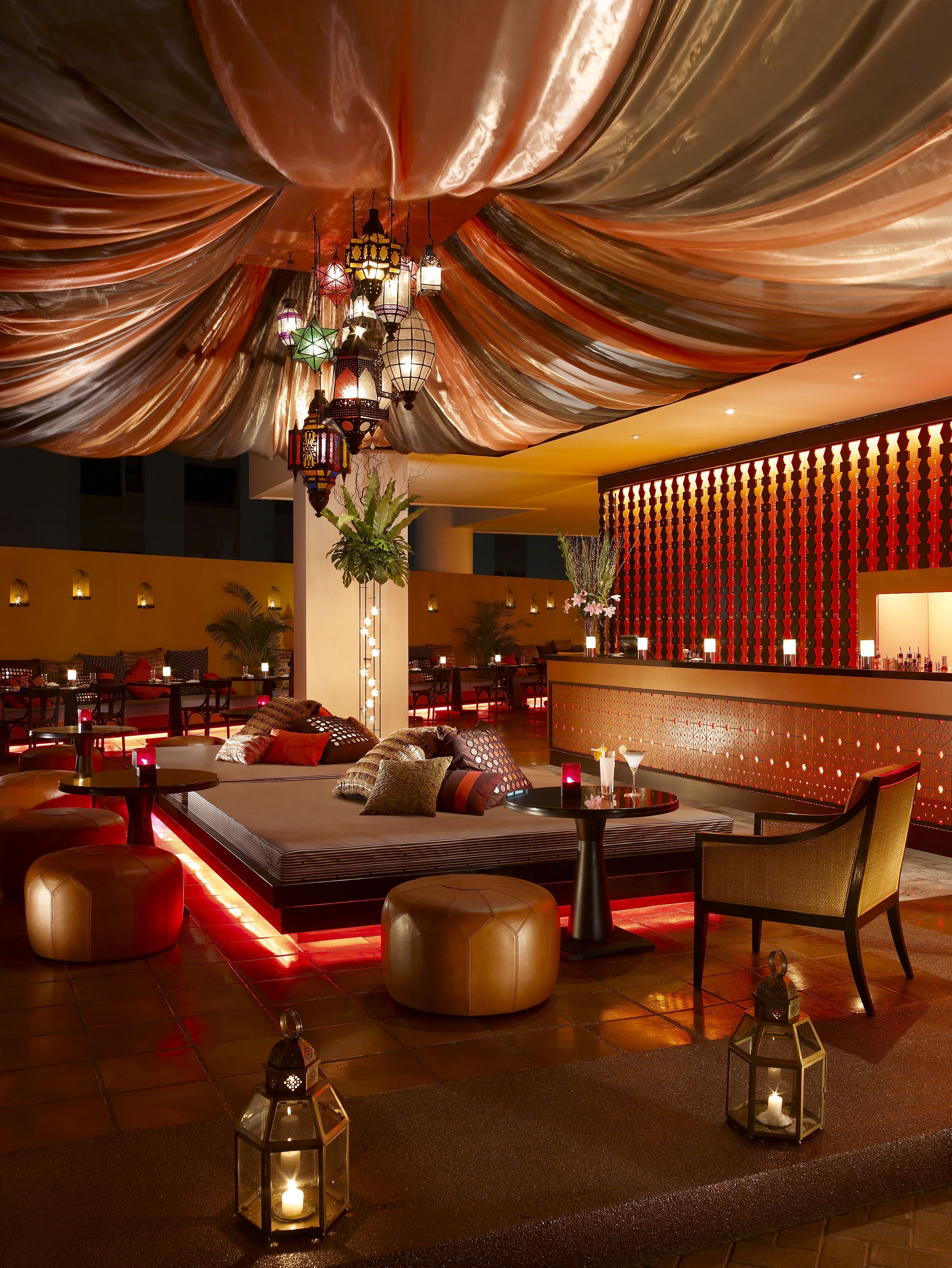 A luxurious lounge area with a sofa, ottomans, and a bar.