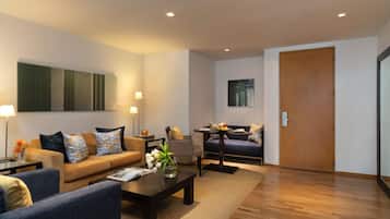 A modern living room with a sofa, armchairs, a coffee table, and a dining area.