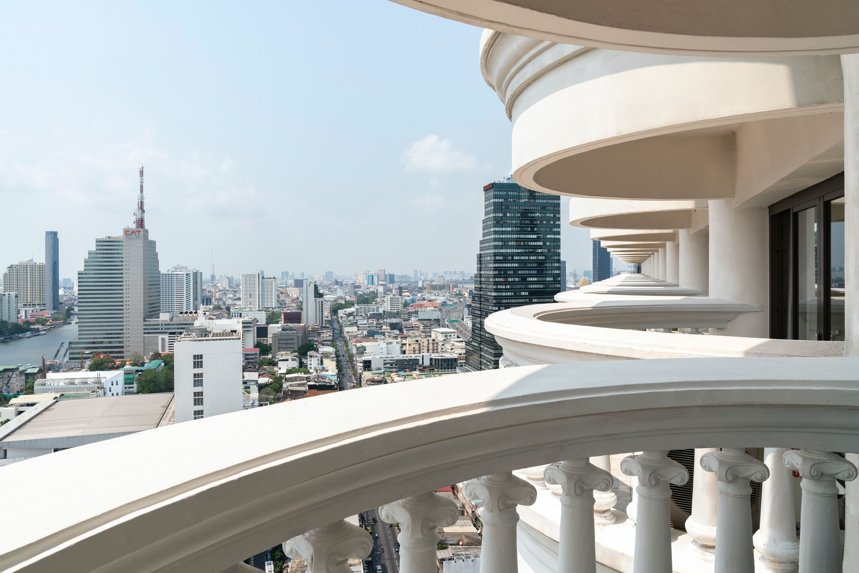 Un balcón con vistas a un paisaje urbano, que incluye edificios altos y un río.