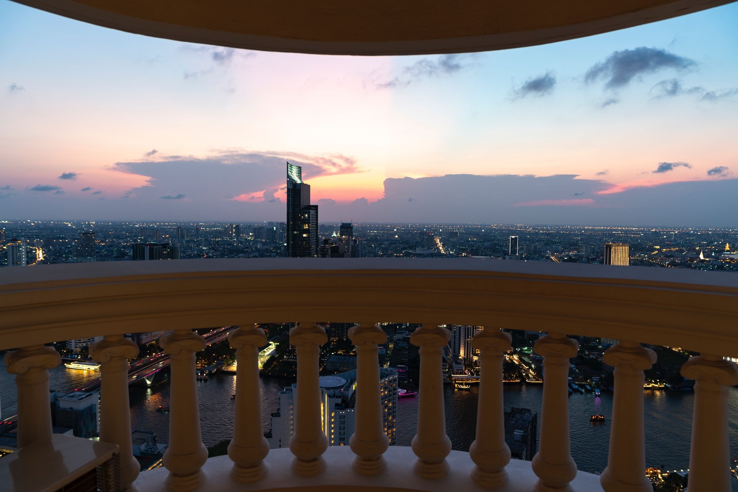 A cityscape at dusk with a view of a river and illuminated buildings.