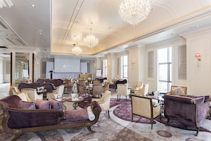 A spacious lobby with elegant furniture, chandeliers, and large windows.