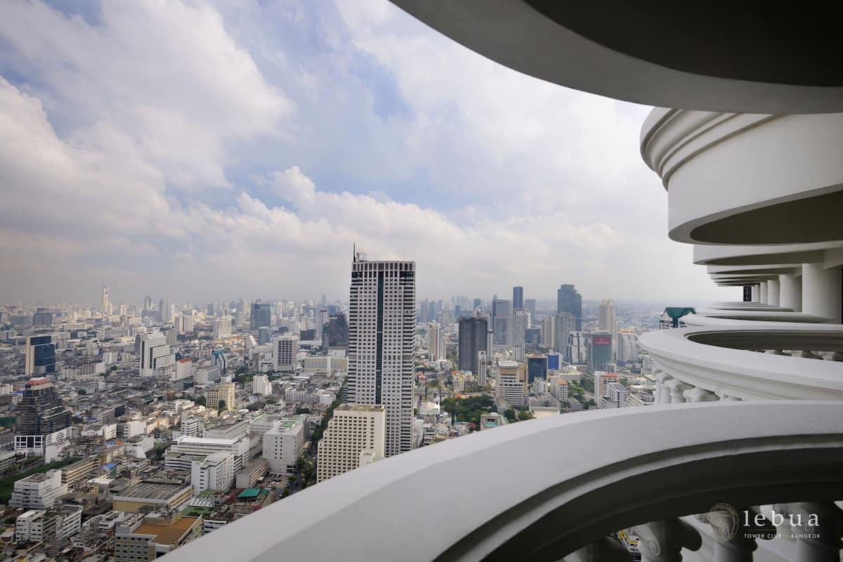A cityscape with a prominent skyscraper and a modern building with a curved balcony.