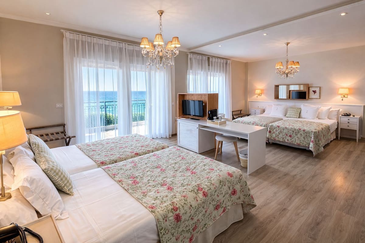Habitación de hotel con dos camas, un escritorio, un televisor y un balcón con vistas.