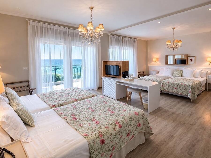 Ett hotellrum med två sängar, ett skrivbord, en TV och en balkong med utsikt.