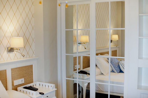 A hotel room with a bed, bedside lamps, a telephone, and a small white table.