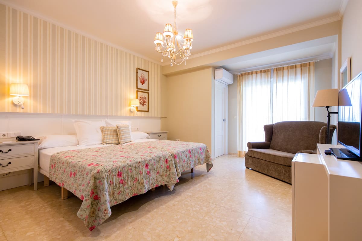 Una habitación de hotel con una cama, un sofá, un televisor y un escritorio.