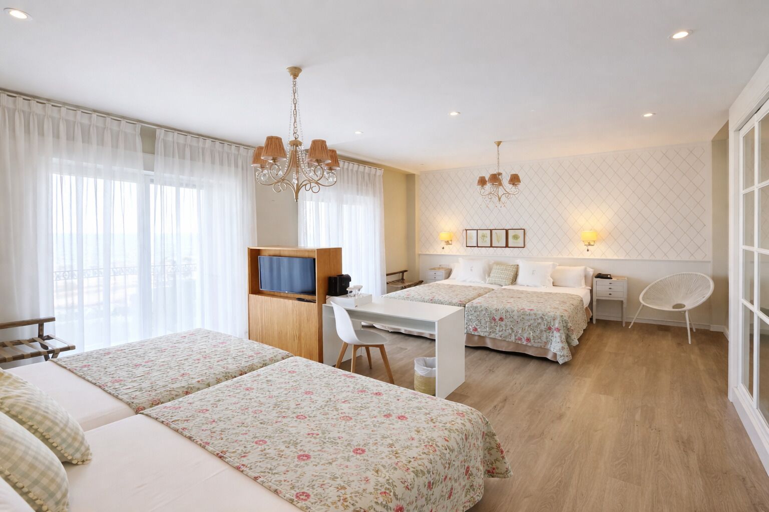 A hotel room with two beds, a desk, a TV, and a chair.