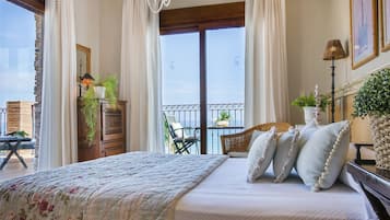 Une chambre avec un grand lit, un balcon avec une chaise et une vue sur la mer.