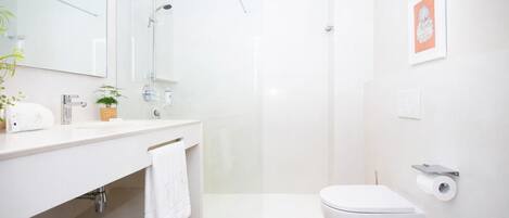 A modern bathroom with a shower, toilet, and sink.