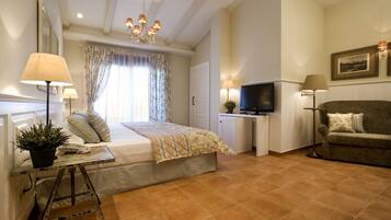 Un dormitorio con cama, lámparas de noche, televisión, sofá y escritorio con lámpara.