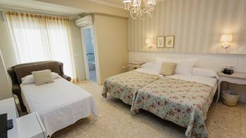 A hotel room with two beds, a chair, a desk, and a bathroom.