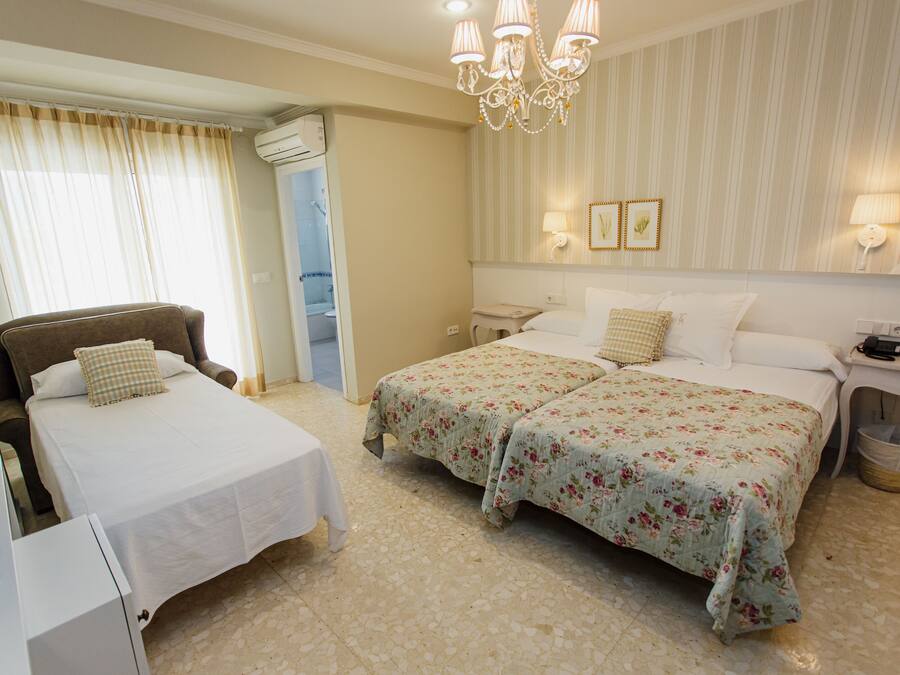 A hotel room with two beds, a chair, a desk, and a bathroom.