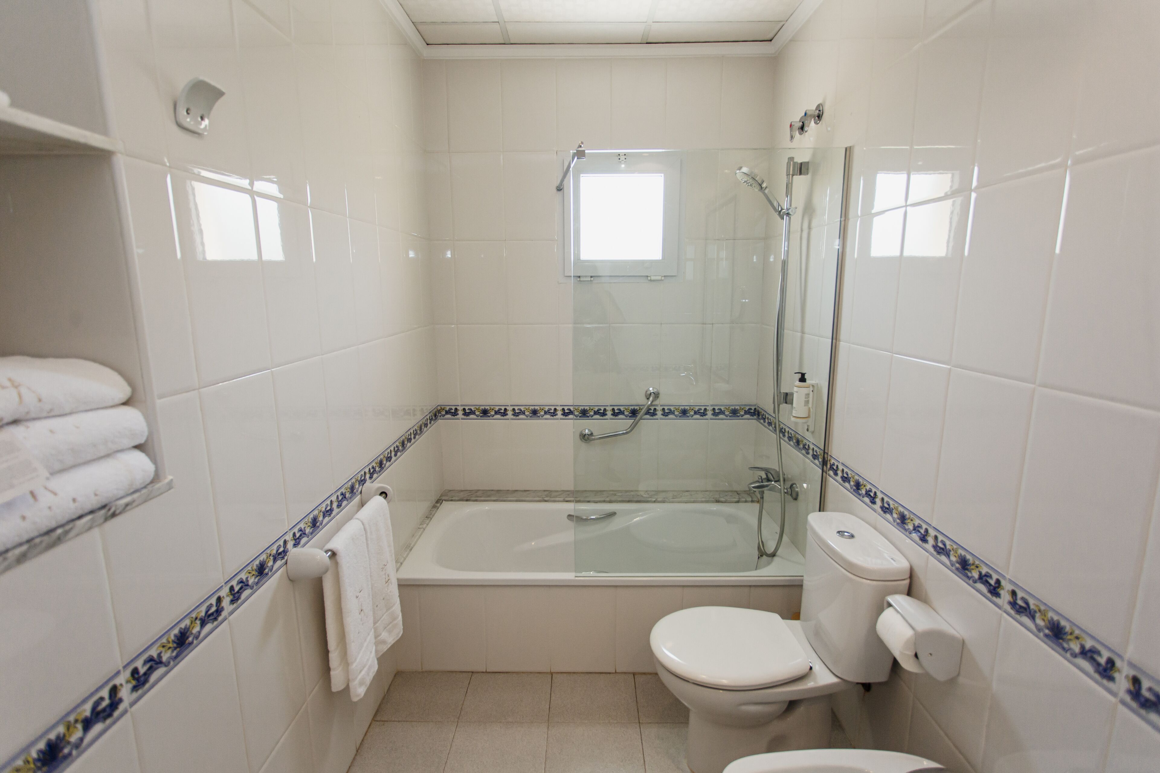 Un baño con ducha de vidrio, inodoro blanco y bañera.