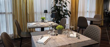 A dining area with a table set for four, including wine glasses, cutlery, and a small plant.