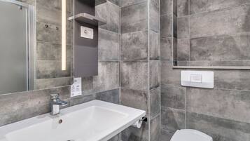 Ein modernes Badezimmer mit einem weißen Waschbecken, einer Toilette und einer Duschkabine.