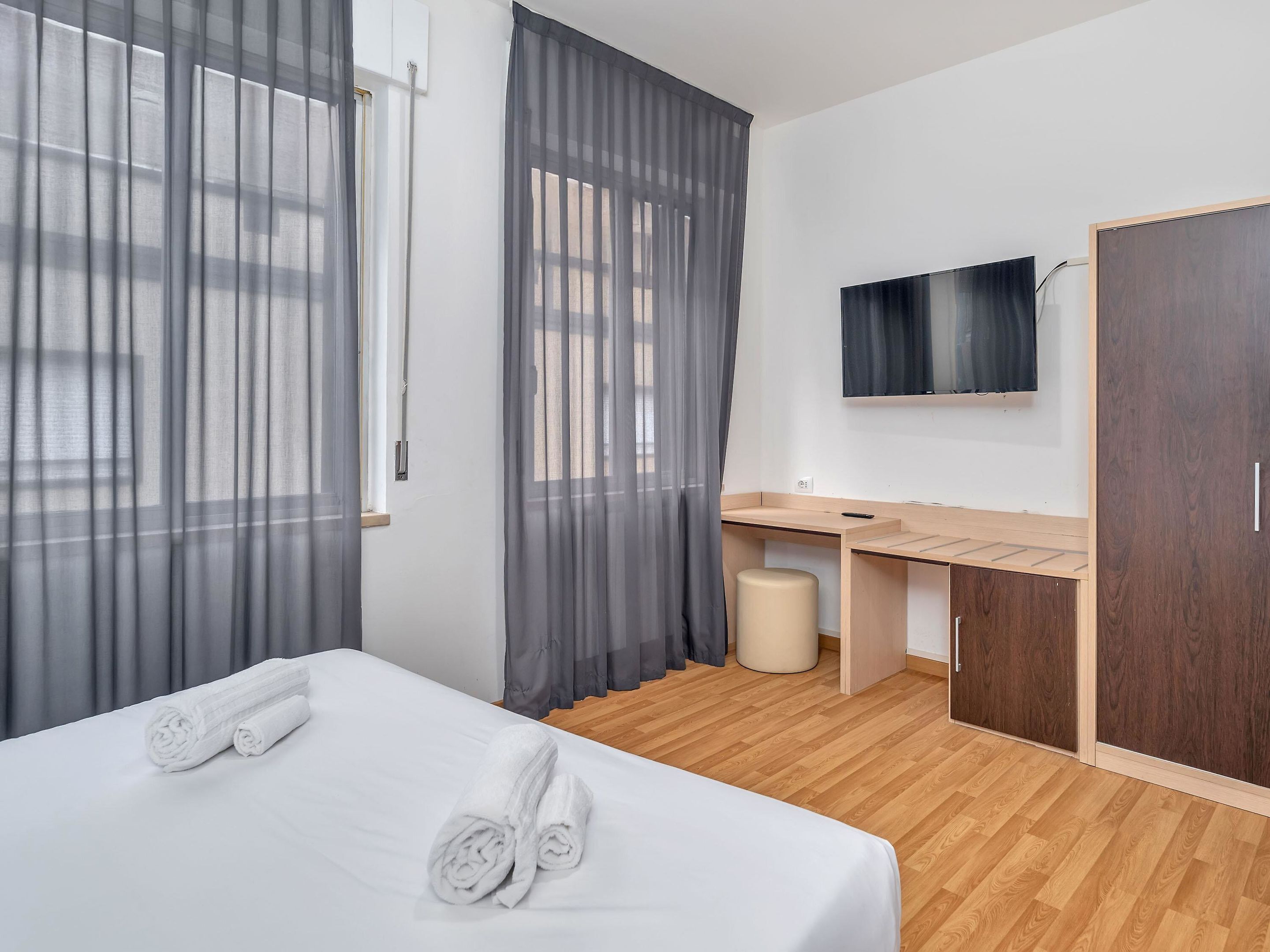 Ein Hotelzimmer mit einem Bett, einem Schreibtisch, einem Sessel, einem Fernseher und einem Kleiderschrank.