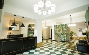 Un vestíbulo de hotel con piso de cuadros, una recepción y una escalera.