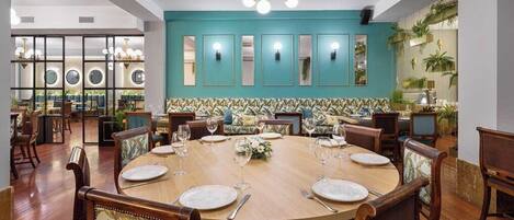 A dining area with a round table set for six, surrounded by wooden chairs with floral upholstery.