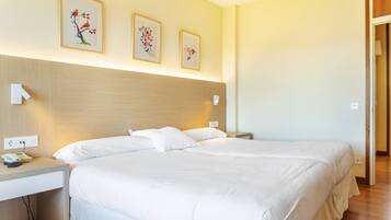Habitación de hotel con dos camas, una mesita de noche con teléfono y una obra de arte en la pared.