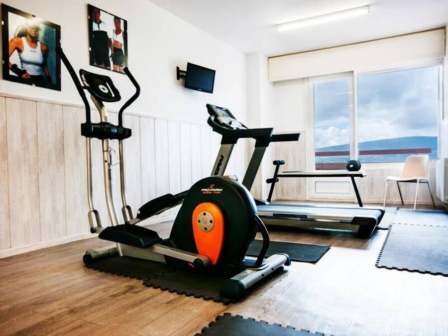 Une salle de sport à domicile équipée d’un vélo d’appartement, d’un tapis de course et d’autres appareils d’exercice.