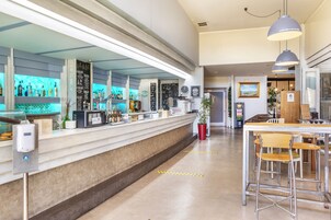 Uma área de bar moderna com um balcão comprido, banquetas e um vaso de planta.
