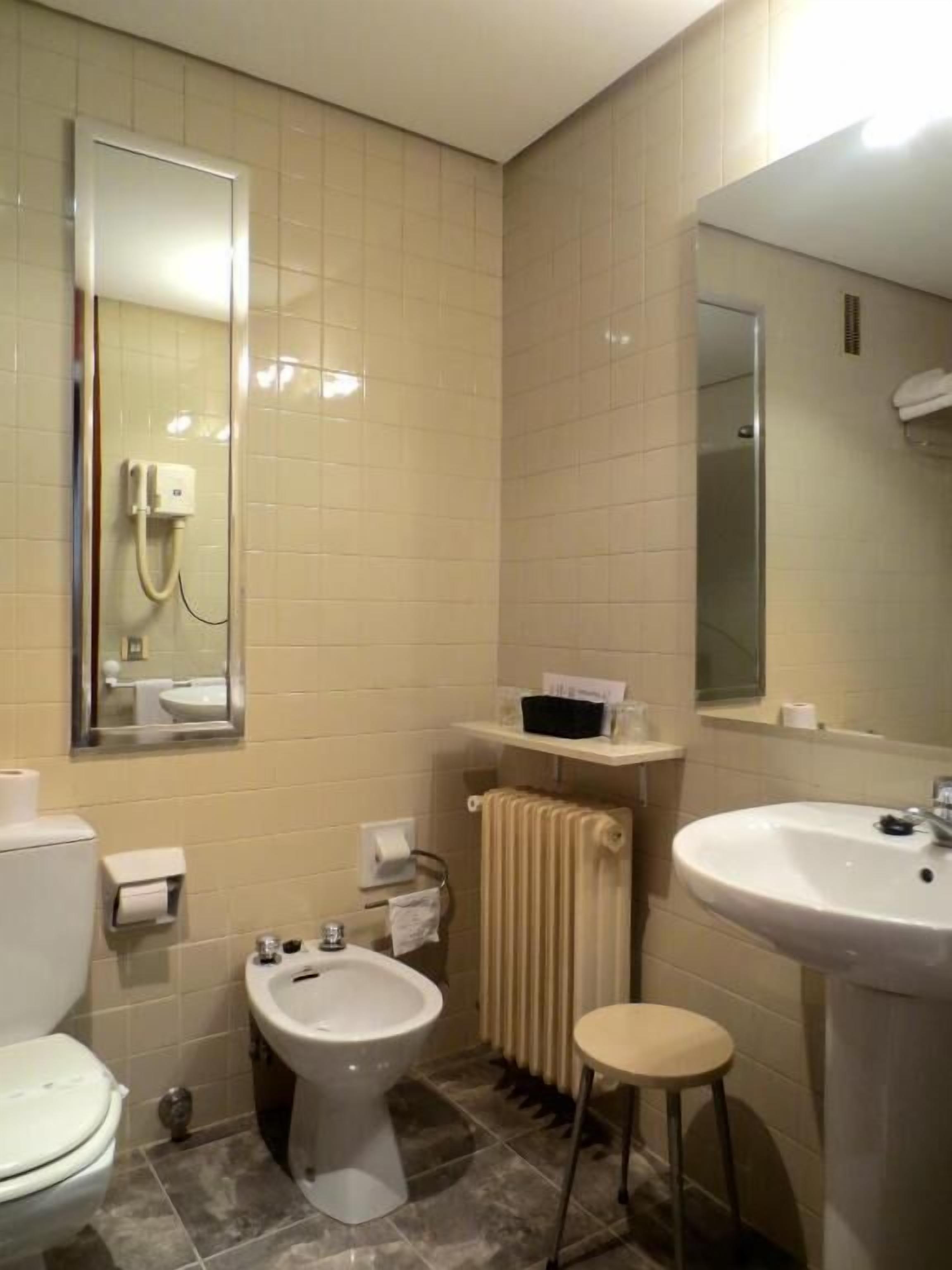 Un baño con inodoro, bidé, lavamanos y espejos.