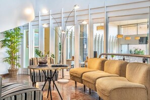 A modern interior with a sofa, a round table, and a potted plant. - Hotel Vejo (Reinosa)