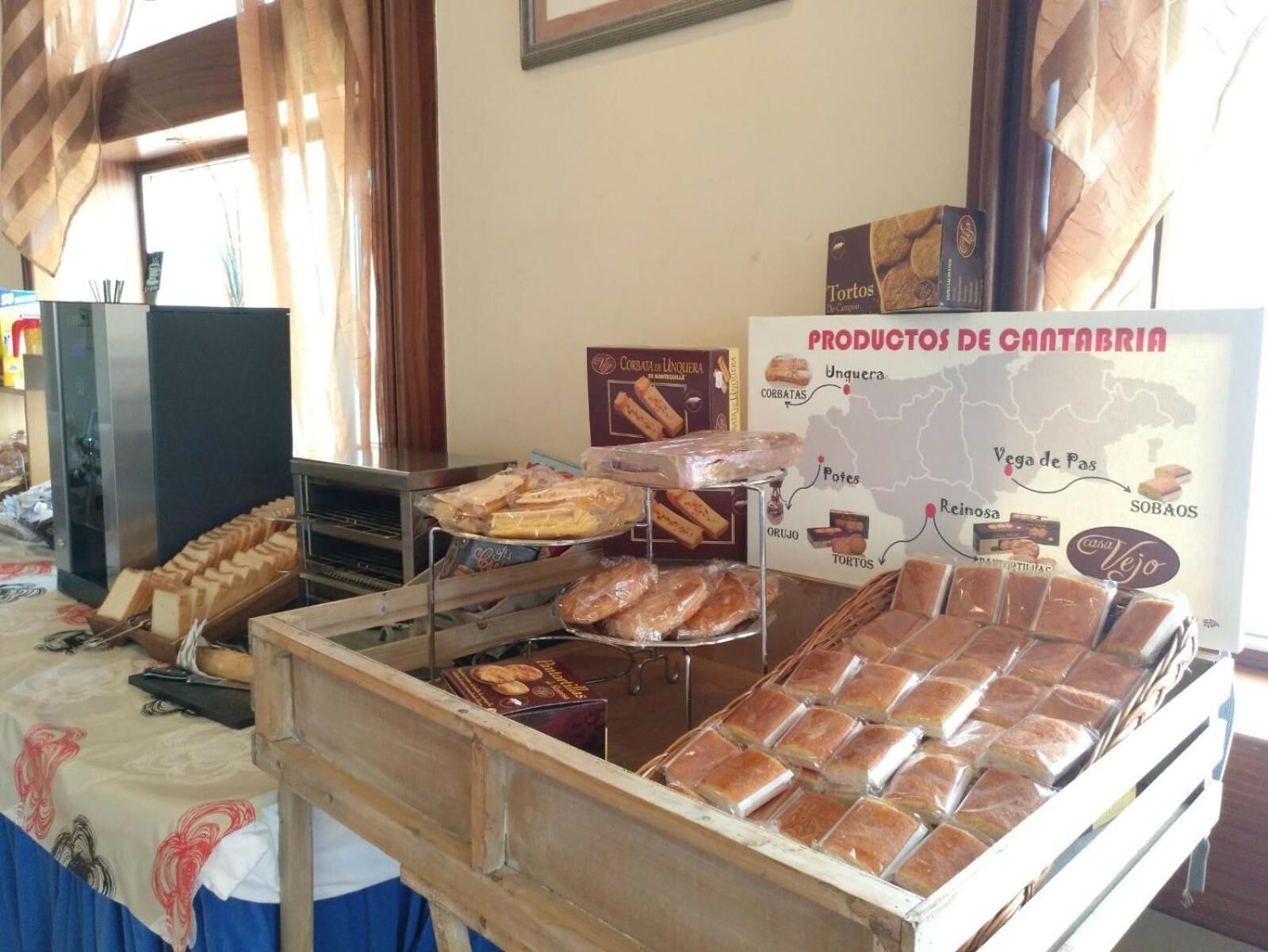 Een bakkerijdisplay met diverse gebakken producten en een bord waarop Cantabria-producten staan vermeld.