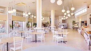 A spacious dining area with multiple tables and chairs, high ceilings with hanging spherical lights, and a kitchen area visible in the background. - Hotel Vejo (Reinosa)