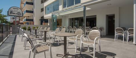 A hotel patio with outdoor seating, a glass entrance, and a sign indicating it is a 4-star establishment.