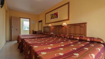A hotel room with four beds, wooden headboards, and a painting on the wall.