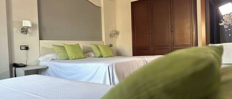 A hotel room with two beds, a nightstand, a telephone, and a large wardrobe.