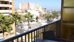 A balcony with a table and chairs, overlooking a parking lot and buildings, with a clear view of the sea. - Hotel Mir Octavio (Algeciras)