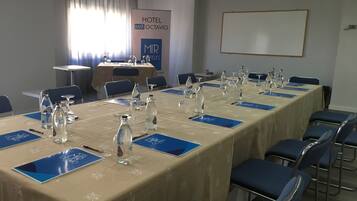 A conference room with a long table set for a meeting, blue nameplates, and water bottles.