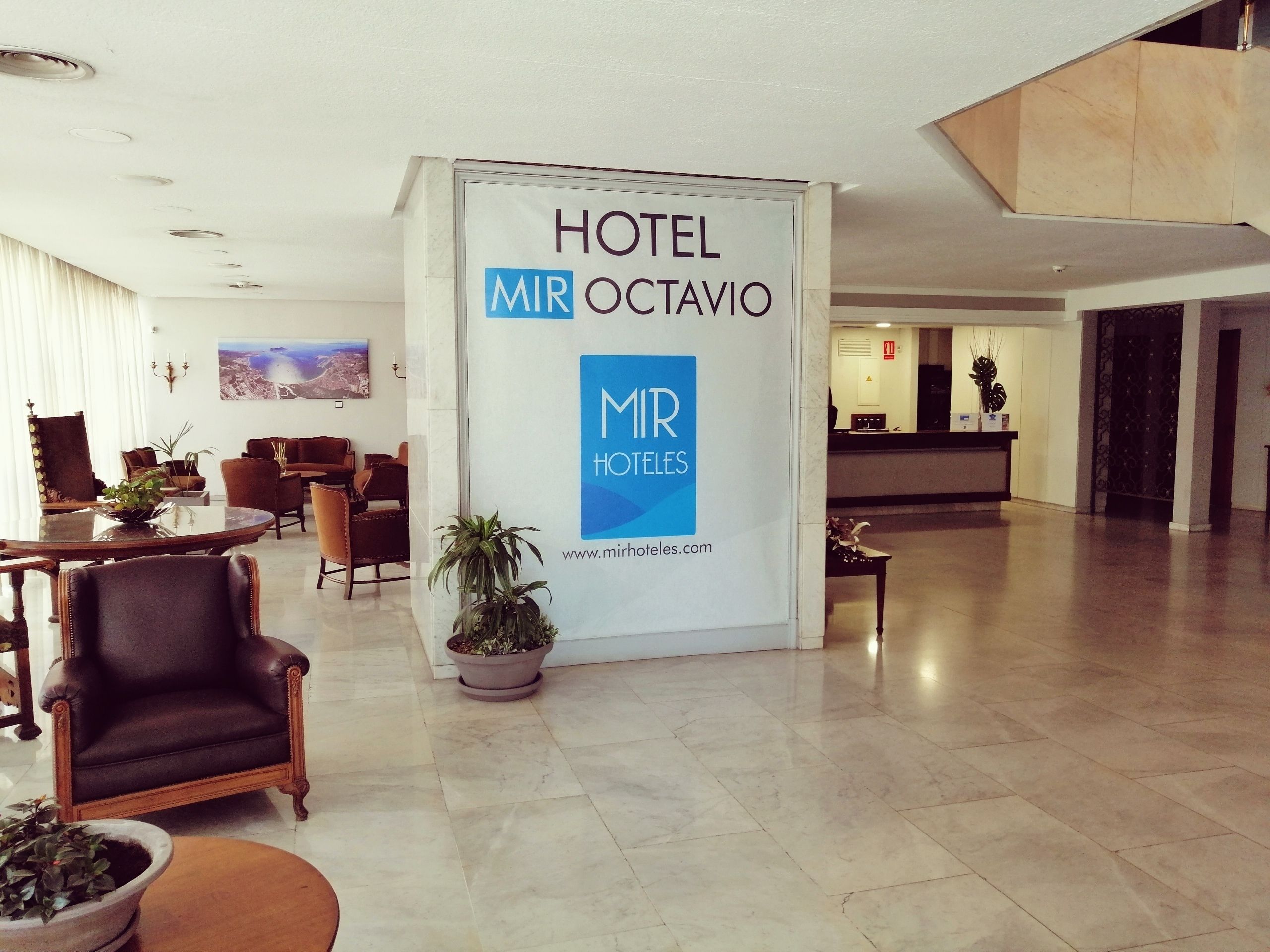 Un hall de hotel con mostrador de recepción, zona de estar y un gran cartel de MIR HOTEL OCTAVIO.