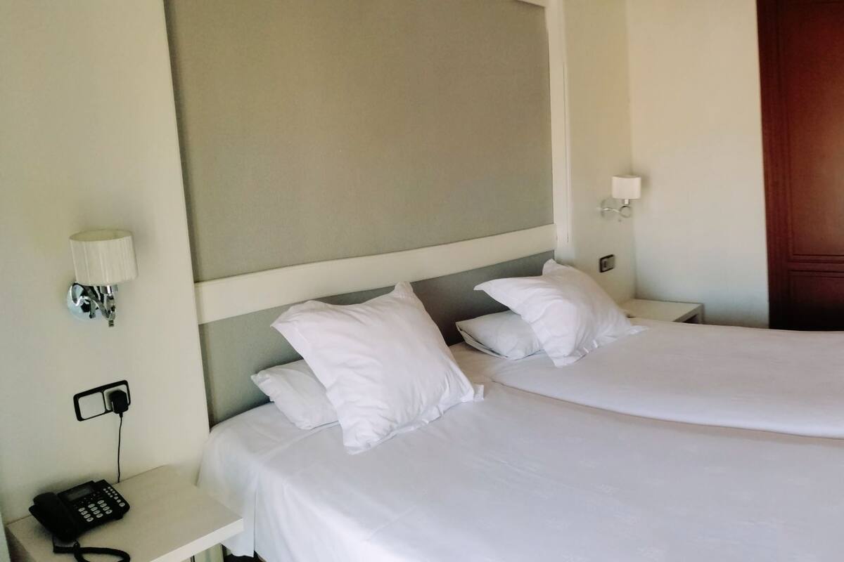 Habitación de hotel con dos camas, televisor, escritorio y armario.